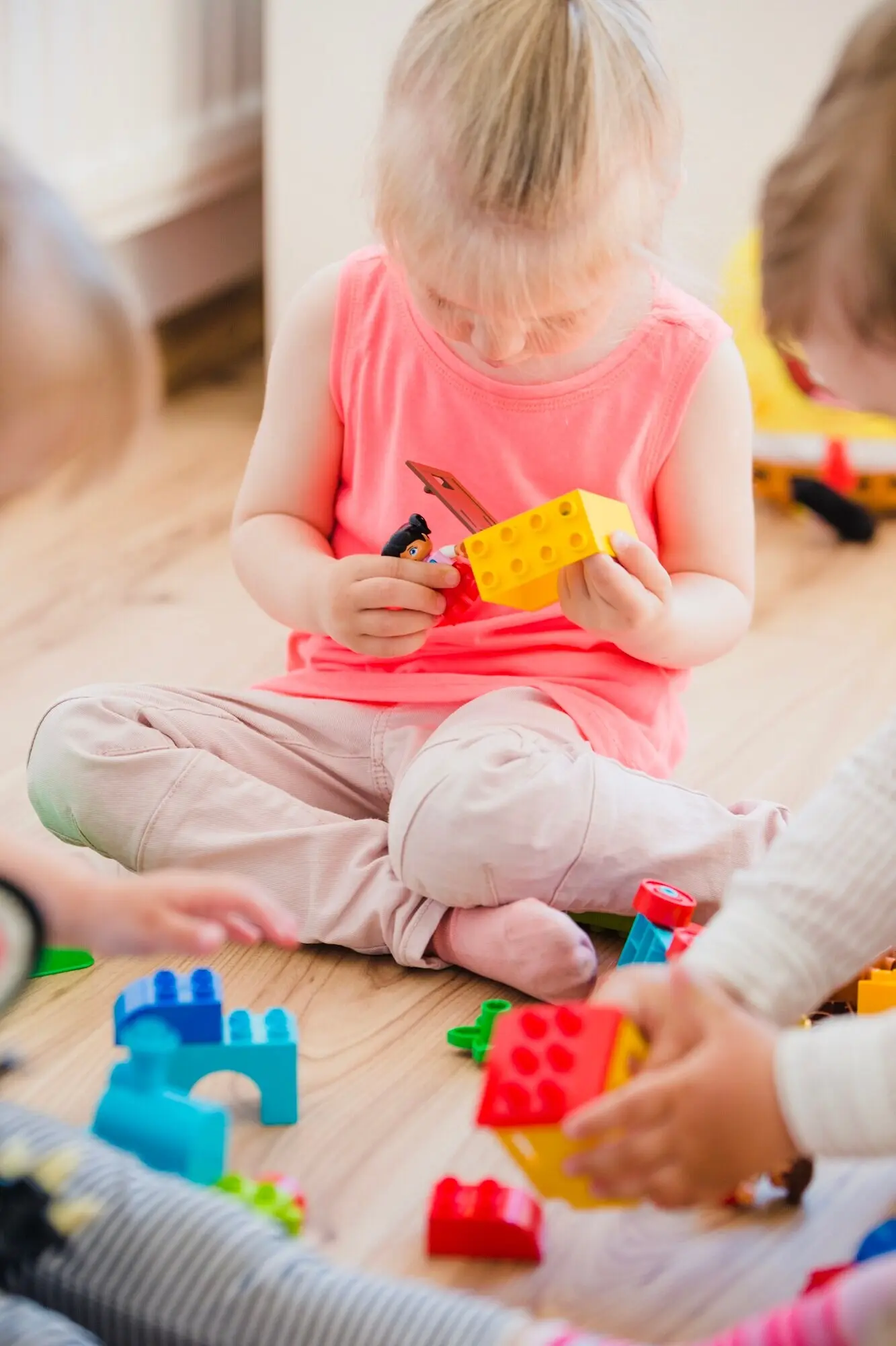 A girl sits on the floor, playing with toys.